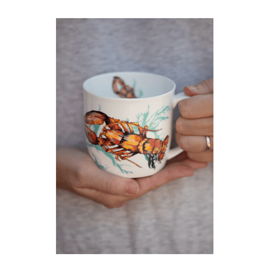 Person holding a mug with a lobster design on a neutral background