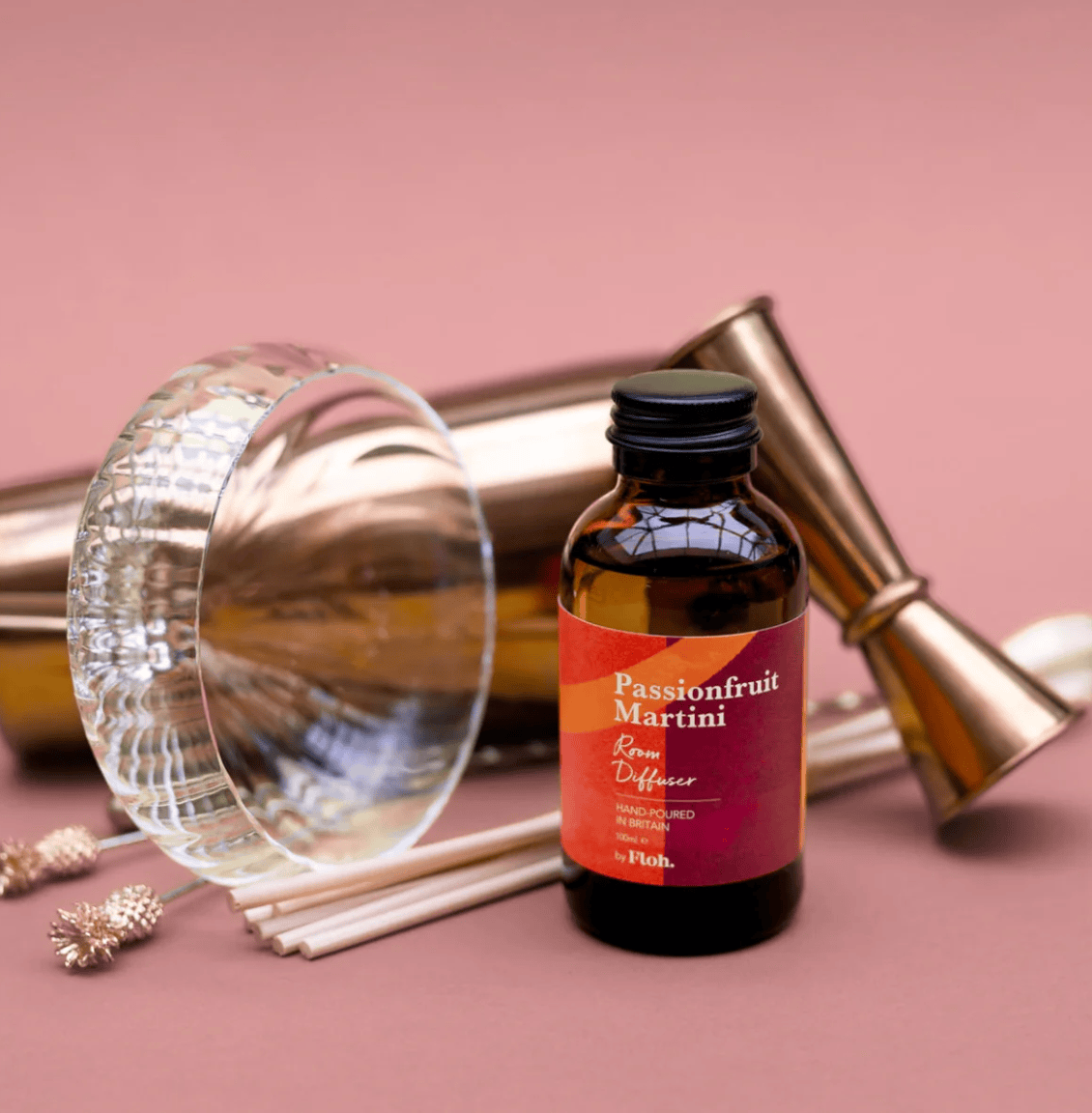 Passionfruit Martini room diffuser bottle with decorative elements on a pink background