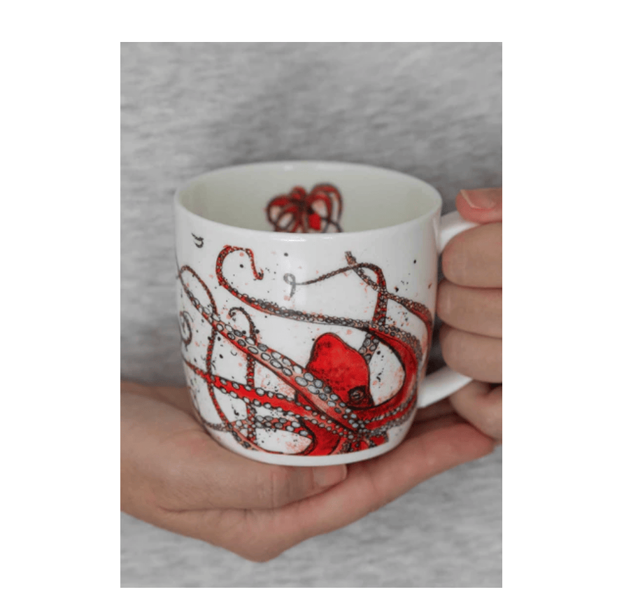 Person holding a mug with a red octopus design against a gray background