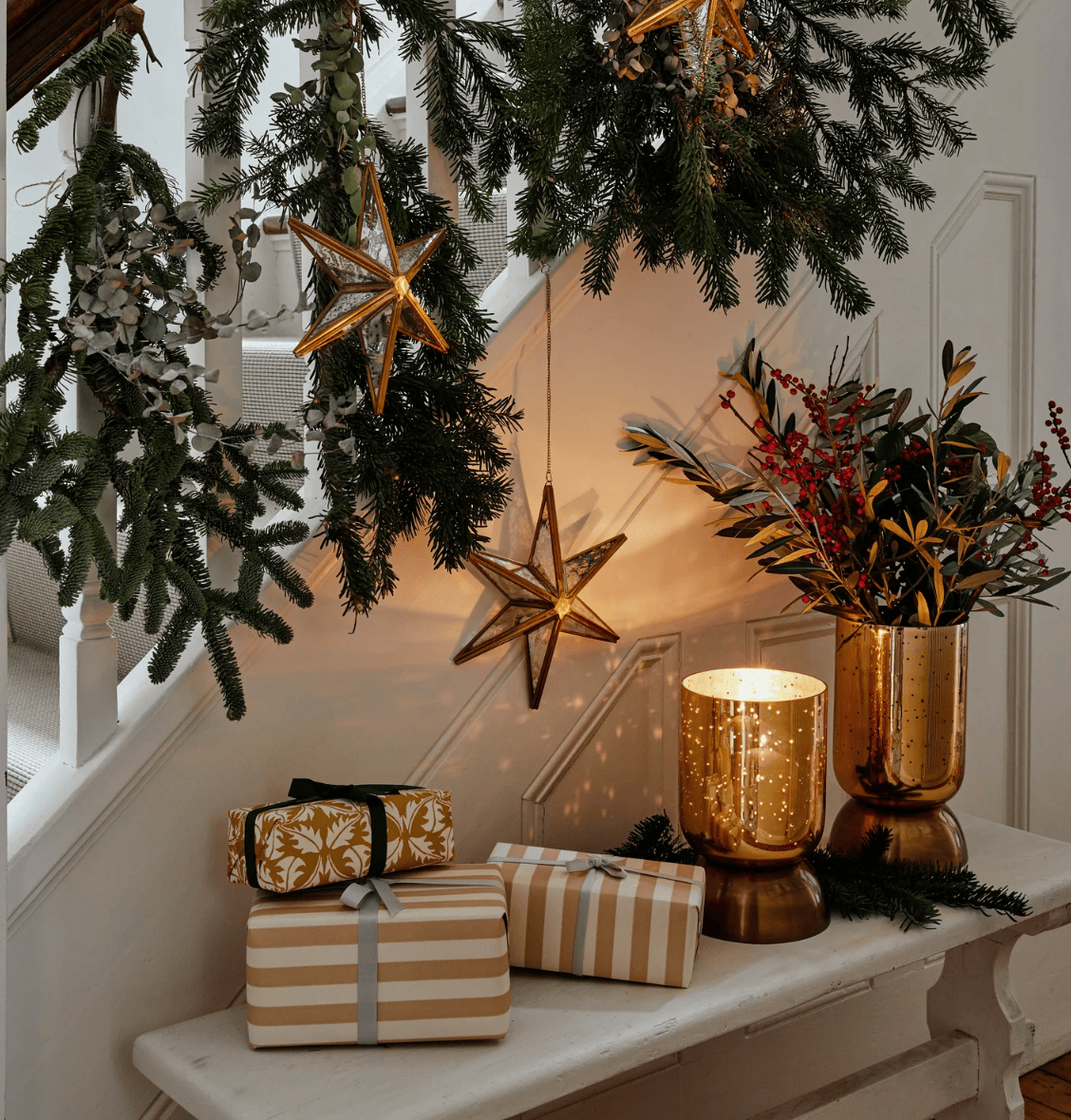 Decorative setup with Christmas lights, presents, and a vase on a staircase.