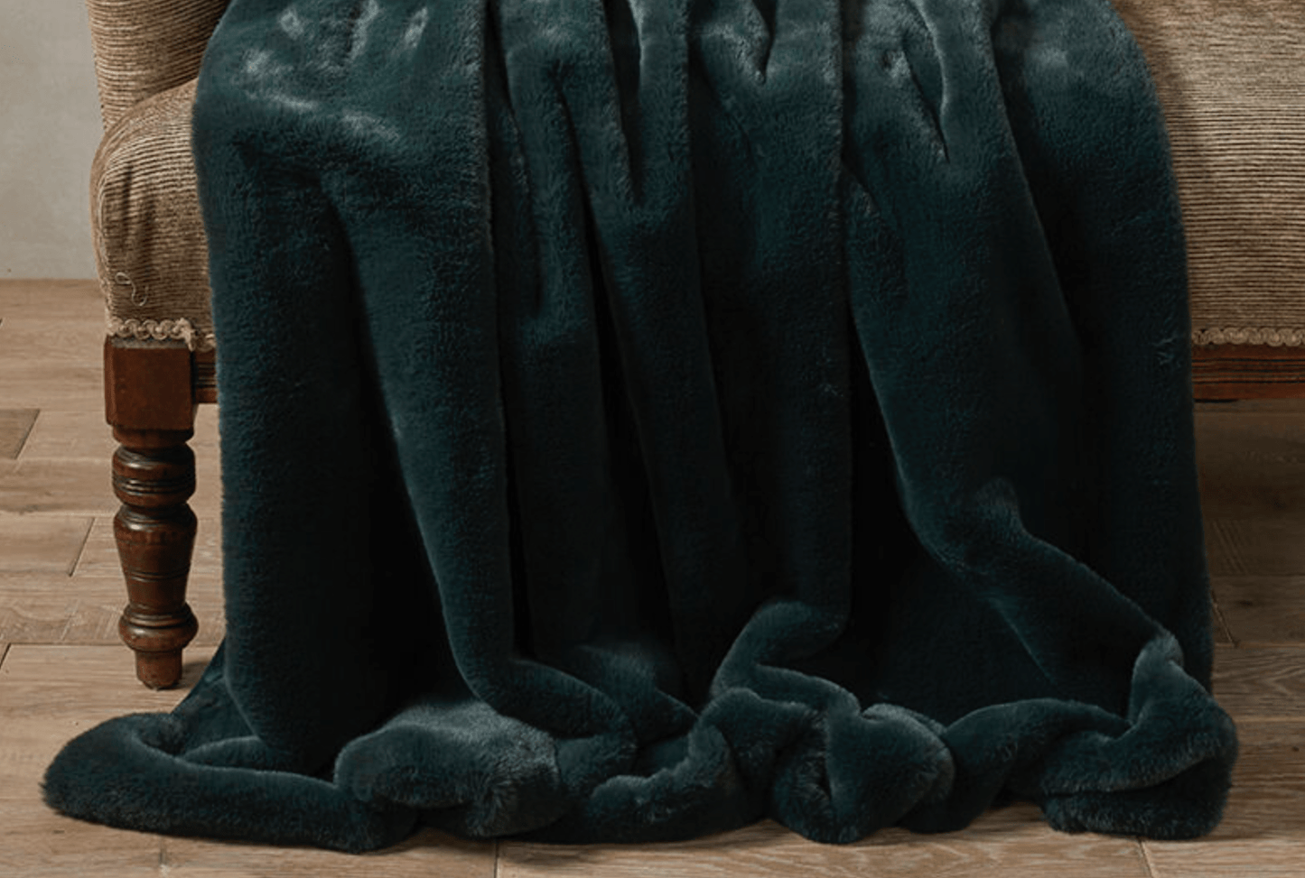 Dark green blanket draped over a chair on a wooden floor