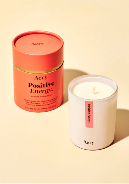 Aery Positive Energy candle and packaging on a beige background