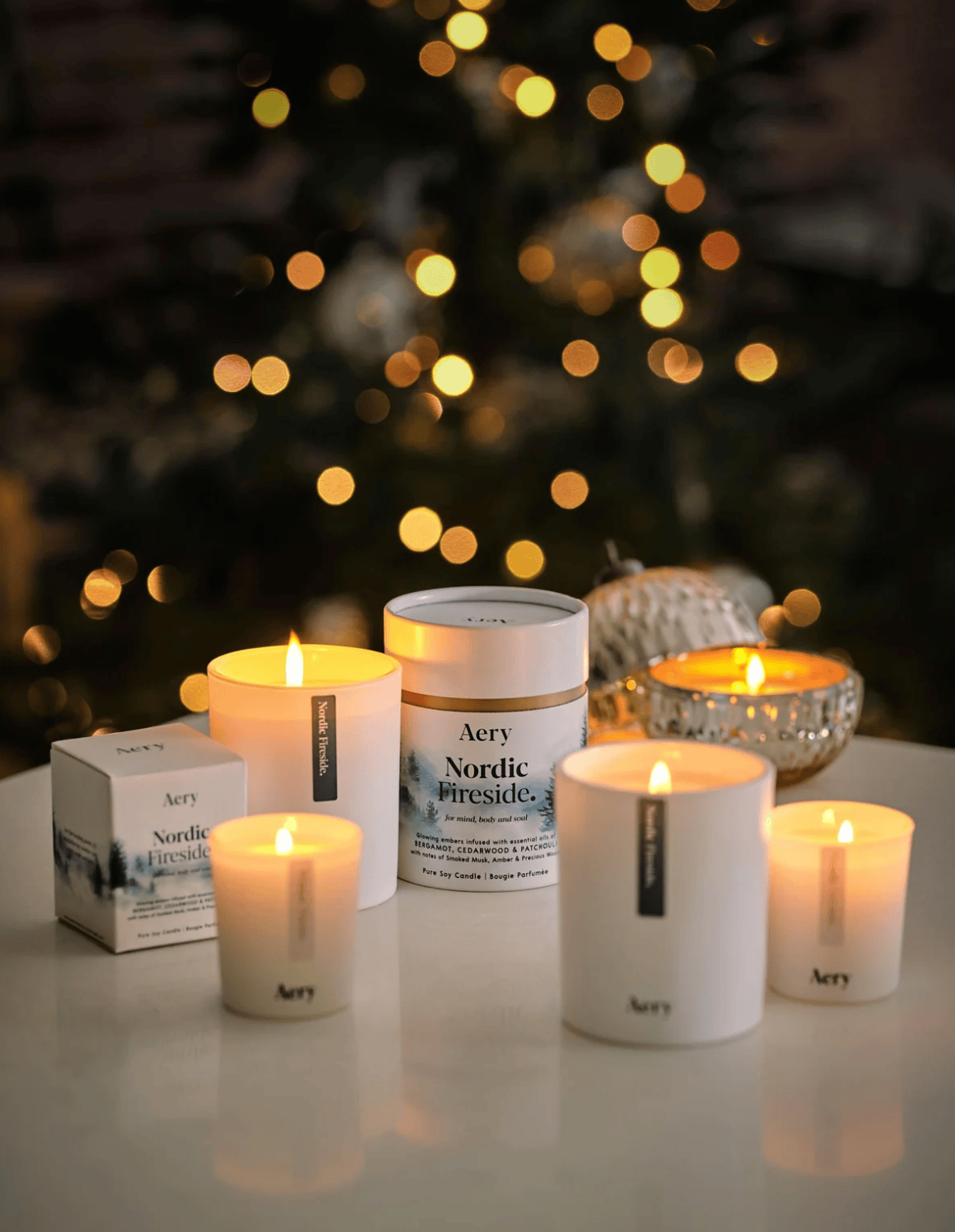Aery candles and packaging on a table with a blurred Christmas tree in the background