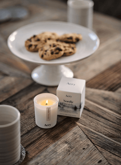 Candle, cookies on a plate, and Aery product on a wooden table