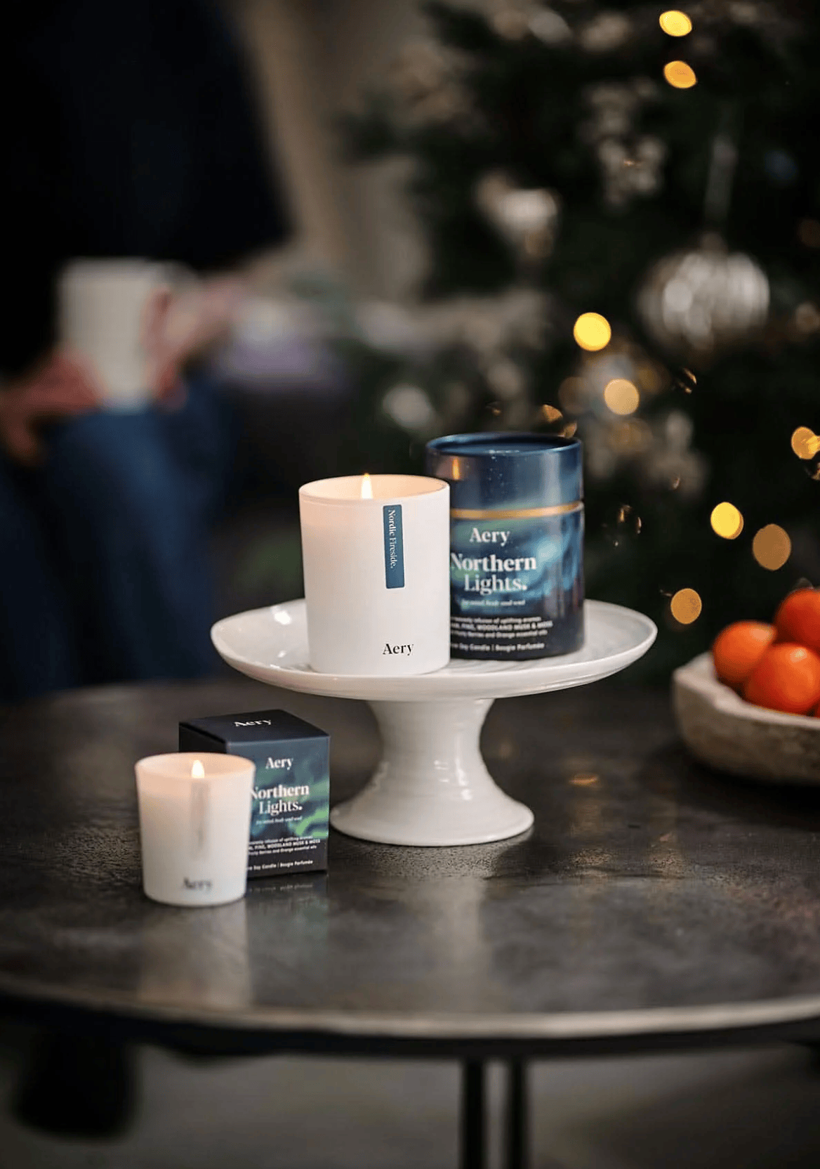 Aery candles and tea on a table with a blurred Christmas tree in the background
