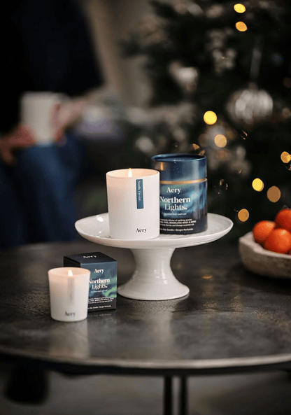 Aery candles and tea on a table with a blurred Christmas tree in the background