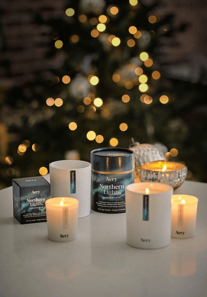 Aery candles and packaging on a table with a blurred Christmas tree in the background