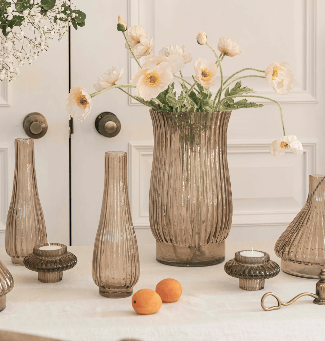 Decorative vases and candles on a table with a white wall background