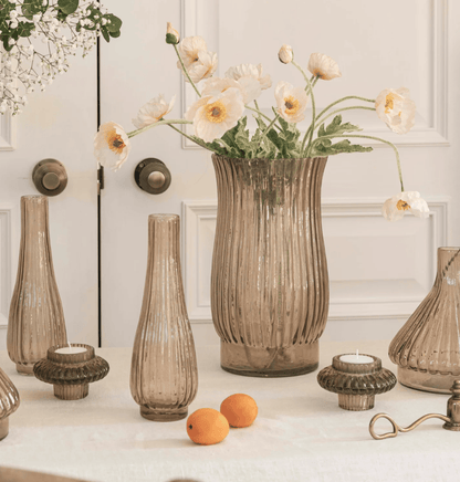 Decorative vases and candles on a table with a white wall background