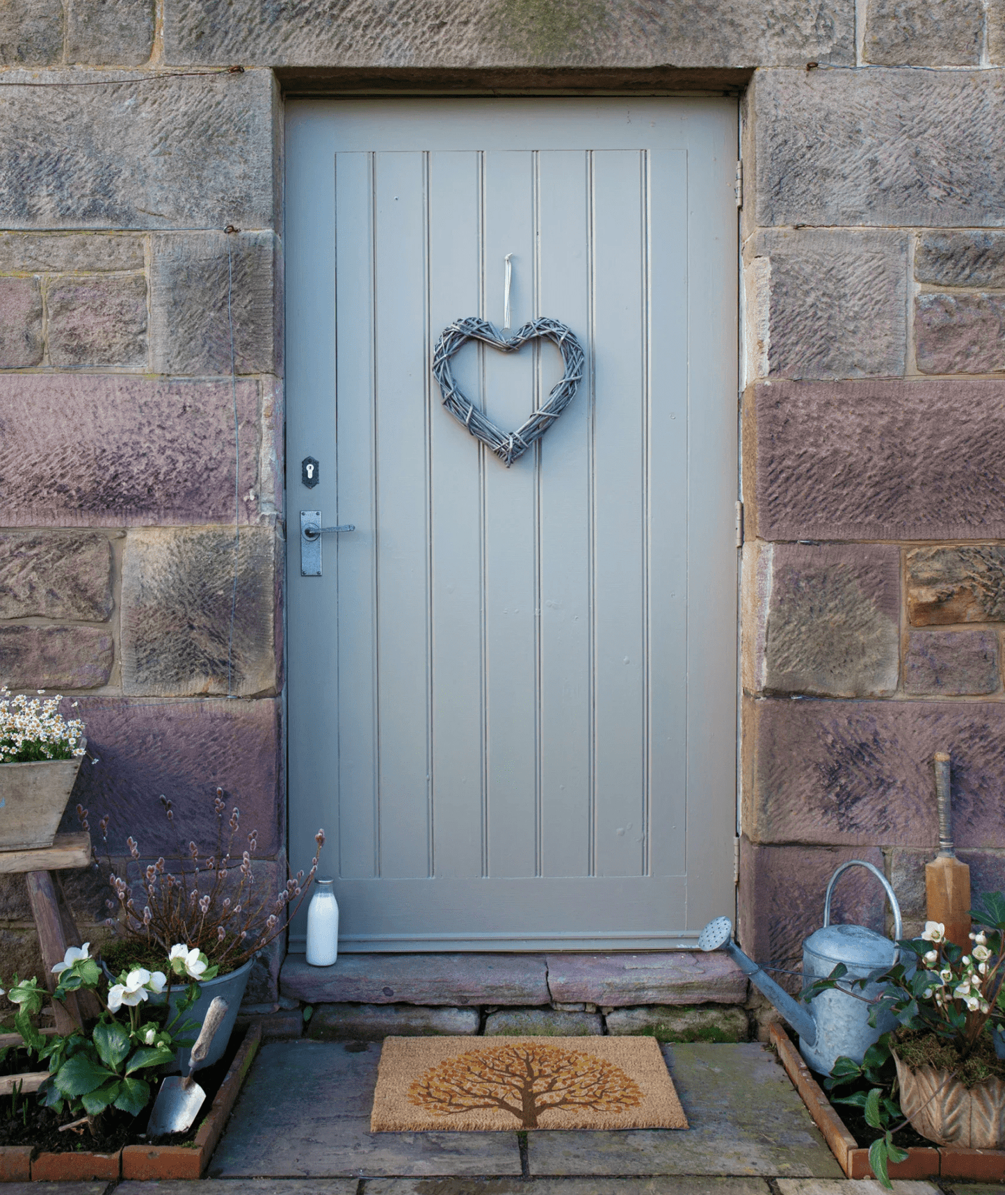 Gray front door with a heart-shaped wreath on a stone wall