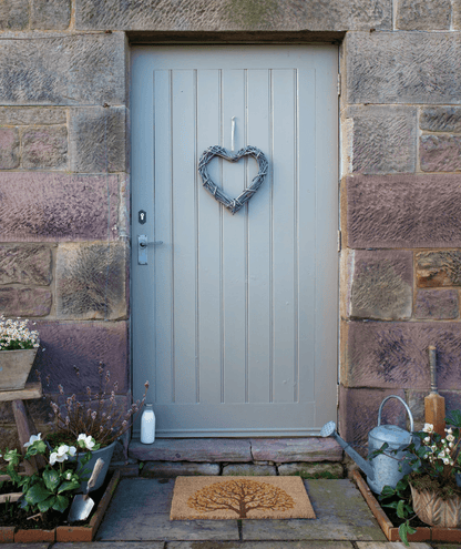 Gray front door with a heart-shaped wreath on a stone wall