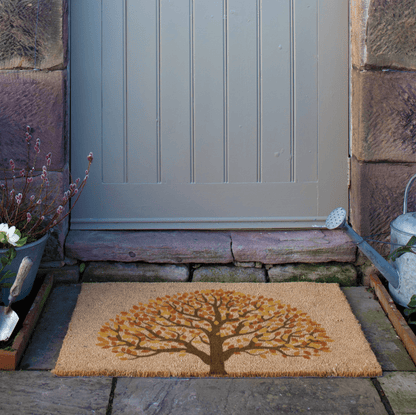 Doormat with tree design in front of a door on a stone path