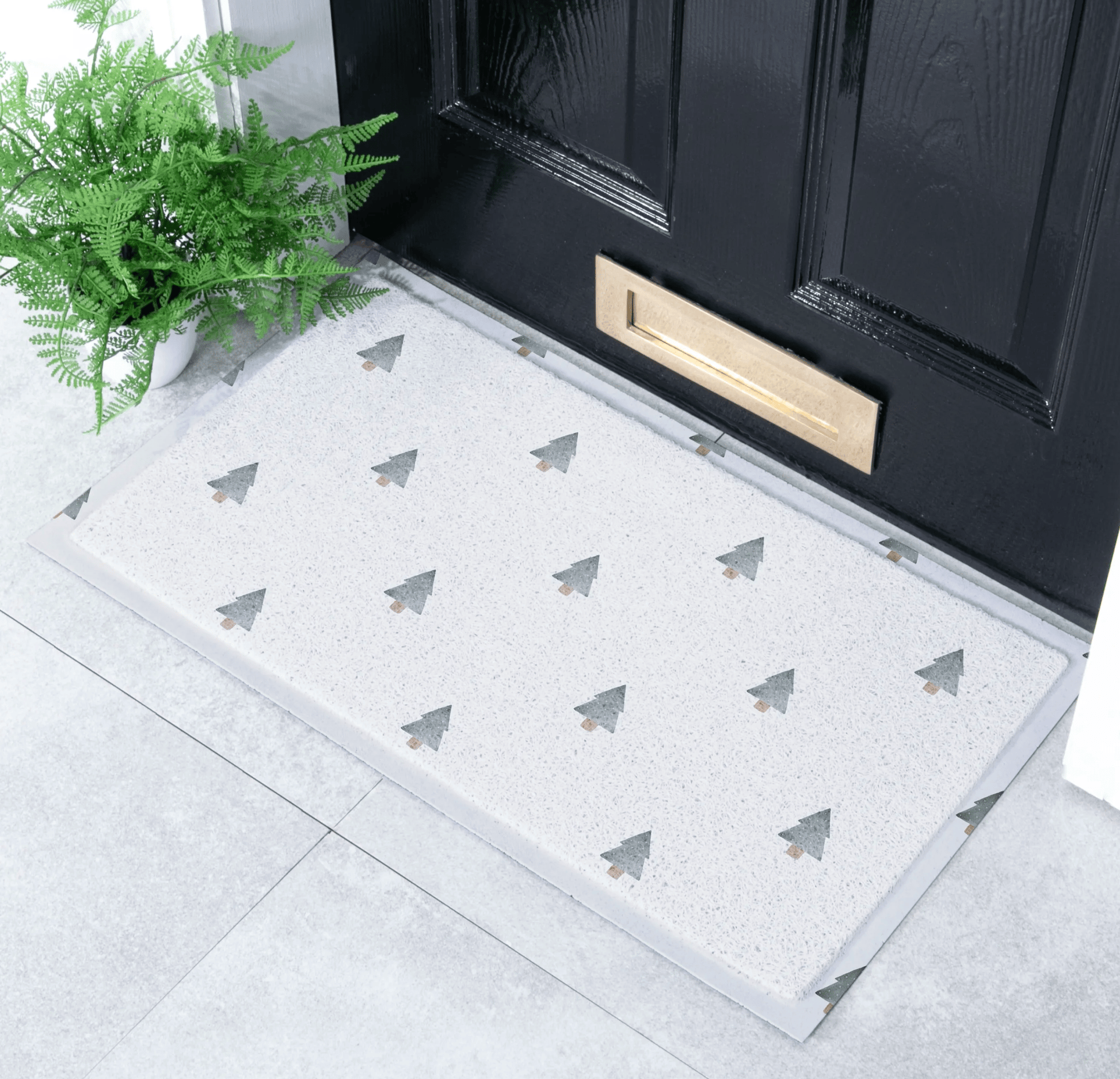Doormat with tree pattern in front of a black door