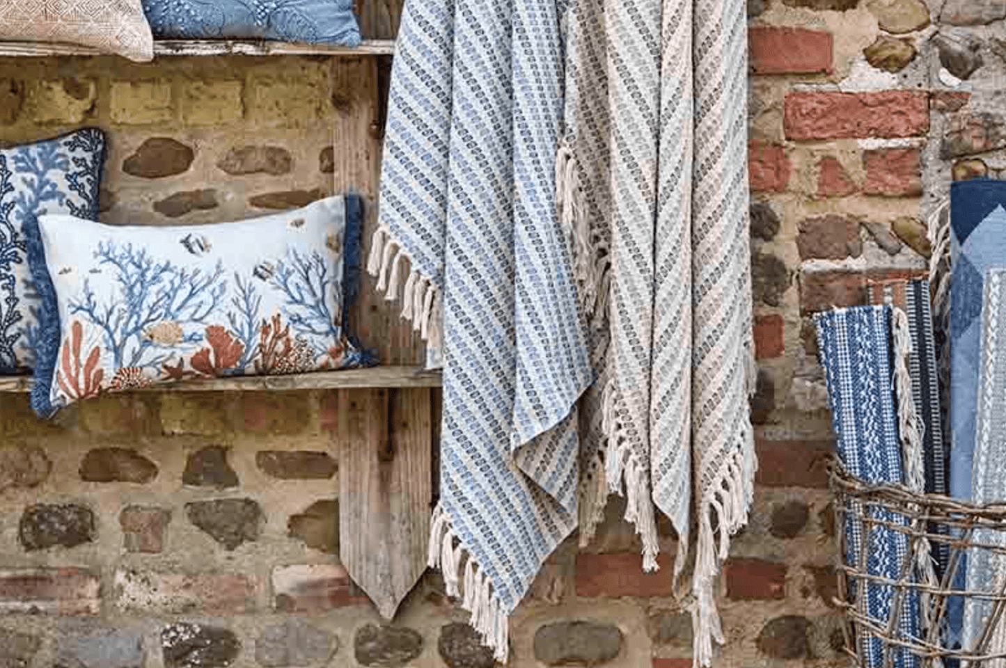 Textiles including pillows and blankets hanging against a stone wall