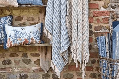 Textiles including pillows and blankets hanging against a stone wall