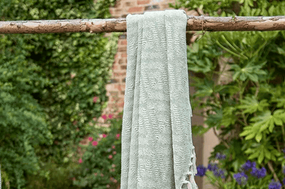 Light green fabric hanging on a wooden stick against a garden background