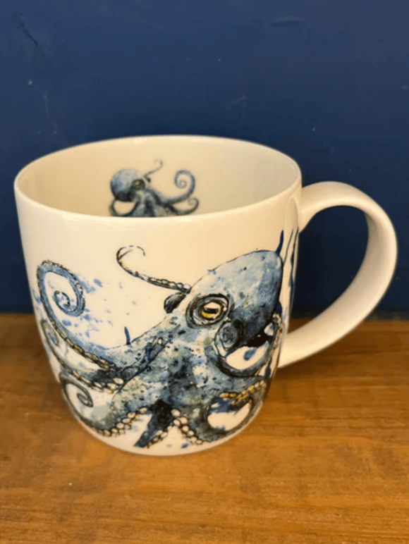 White mug with an octopus design on a wooden surface and dark blue background