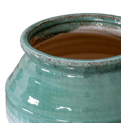 Close-up of a teal ceramic pot with a brown interior on a white background