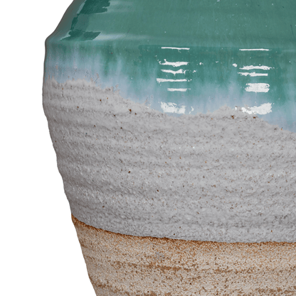 Close-up of a ceramic vase with a textured base and greenish top on a white background