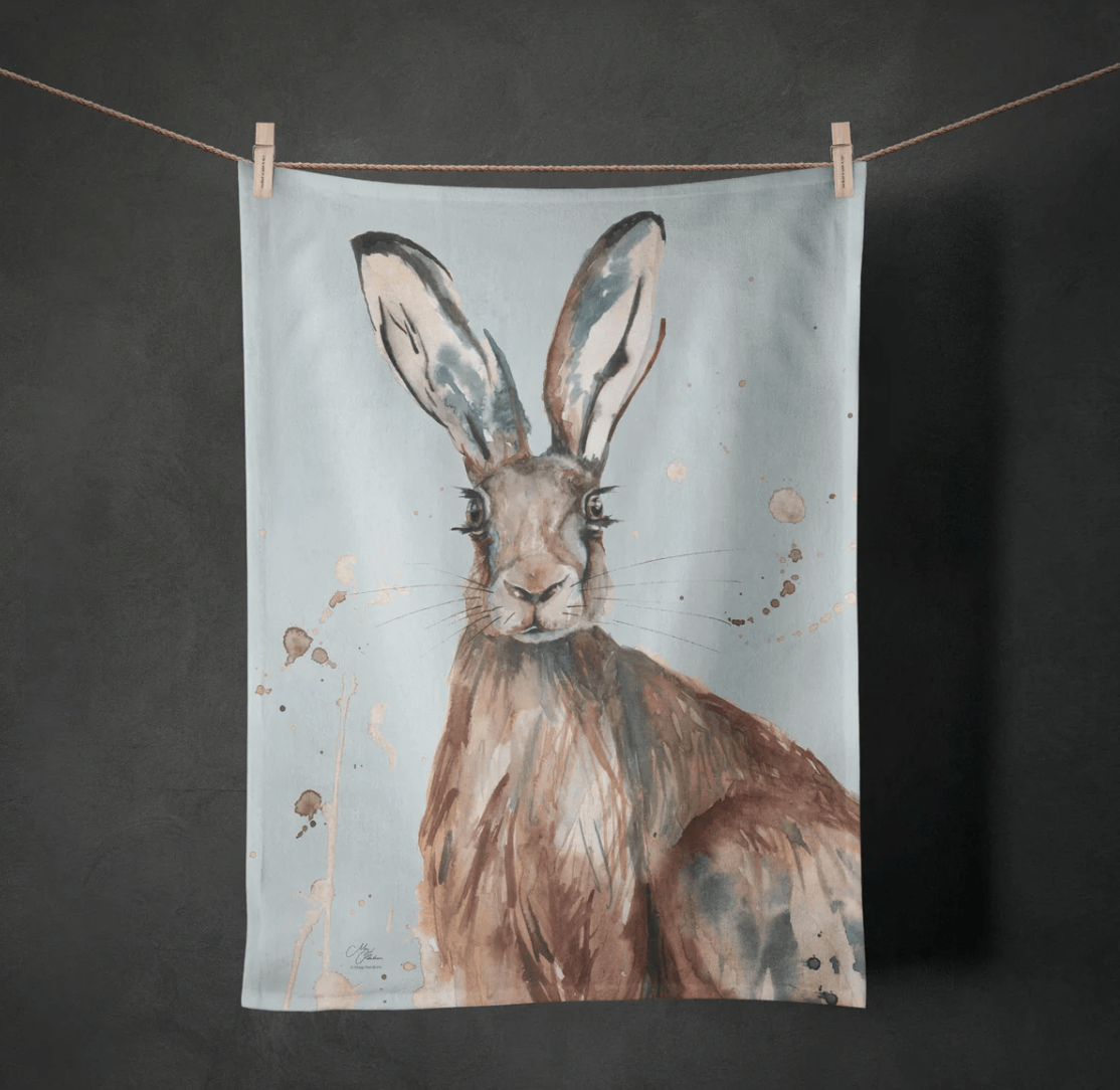 Tea towel with a rabbit design hanging on a line against a dark background