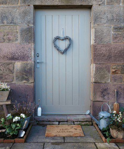 Gray front door with heart-shaped wreath on stone wall