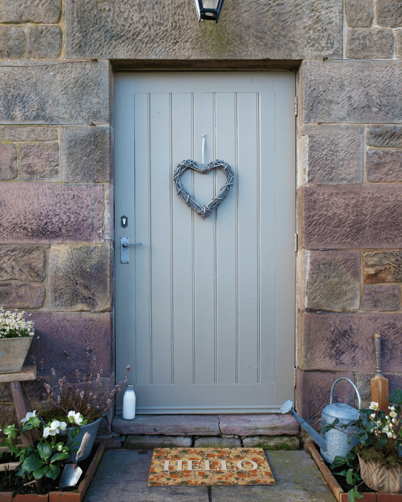 Gray front door with heart-shaped wreath on stone wall