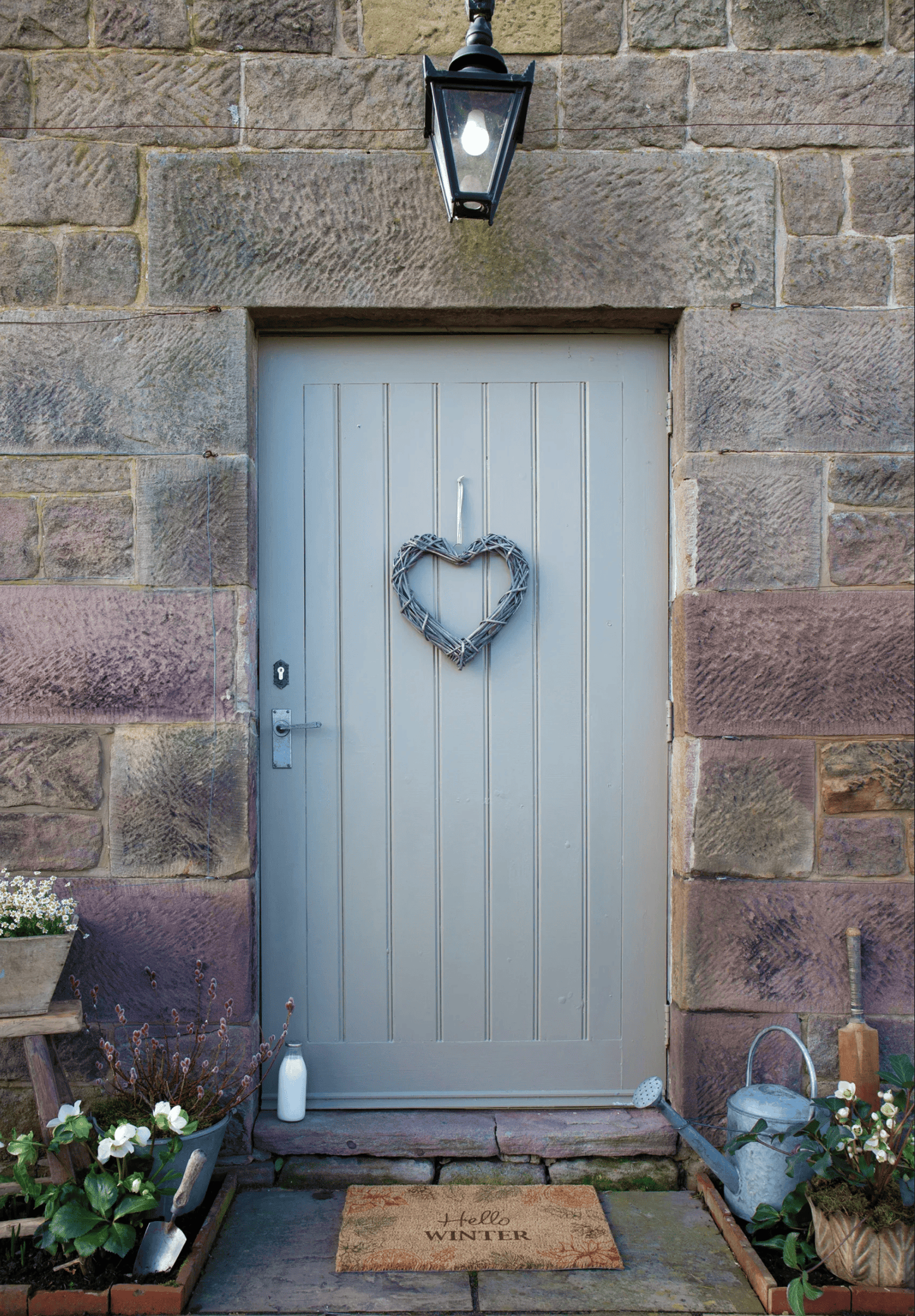 Grey front door with heart-shaped wreath on stone wall