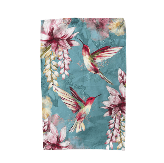 Floral and hummingbird patterned towel with pink flowers and green leaves on a blue background