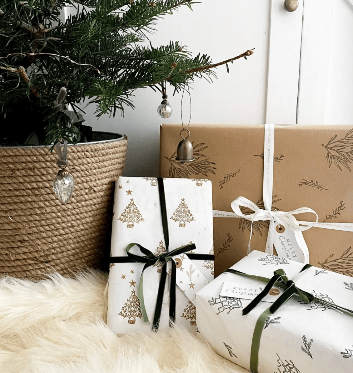 Gifts wrapped in festive paper with Christmas tree designs, placed under a decorated tree.