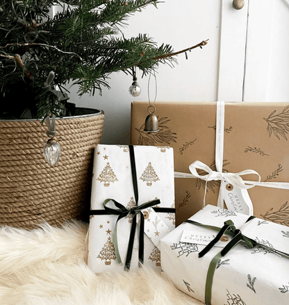 Gifts wrapped in festive paper with Christmas tree designs, placed under a decorated tree.