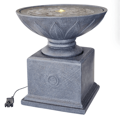 A gray stone-look outdoor fountain with a square pedestal base, a lotus-shaped bowl, and a small glowing flame effect visible in the water. A power cord is attached at the lower left, photographed on a plain white background.