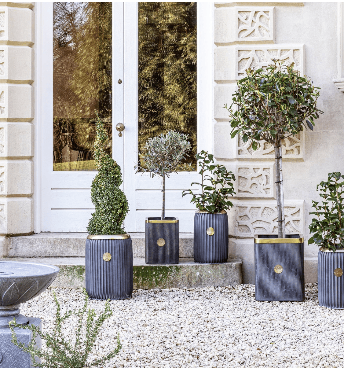Decorative potted plants in front of a white door with decorative elements.