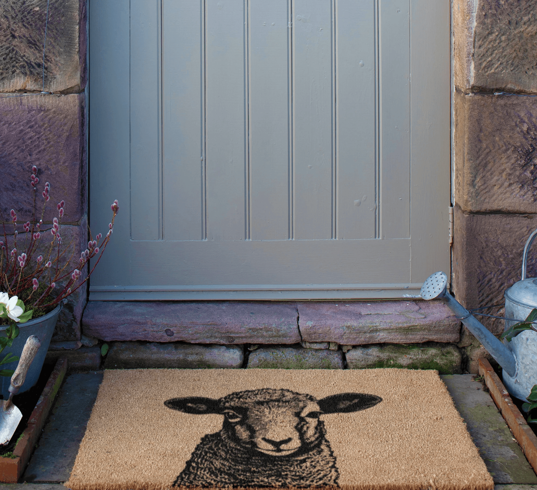 Doormat with a Lamb design in front of a door with stone walls.