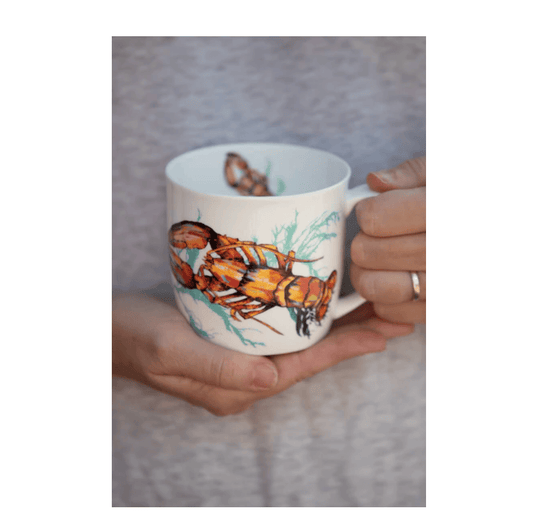 Person holding a mug with a lobster design on a neutral background