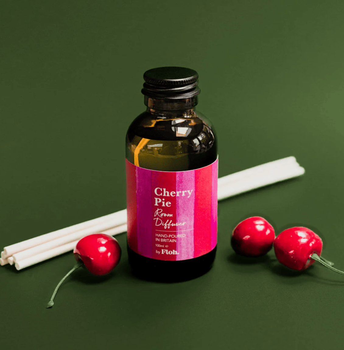 Bottle of 'Cherry Pie' room diffuser with cherry-themed packaging on a green background