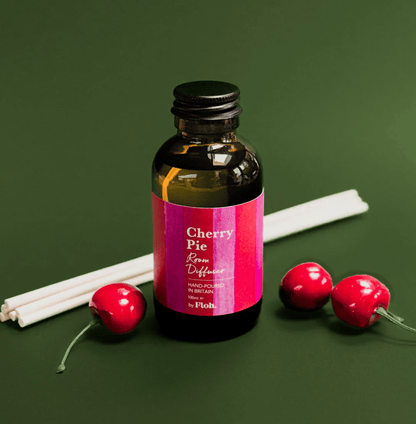 Bottle of 'Cherry Pie' room diffuser with cherry-themed packaging on a green background