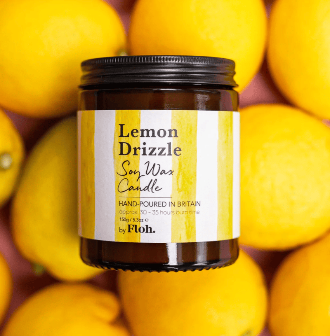Lemon Drizzle soy wax candle jar with a label on a background of lemons