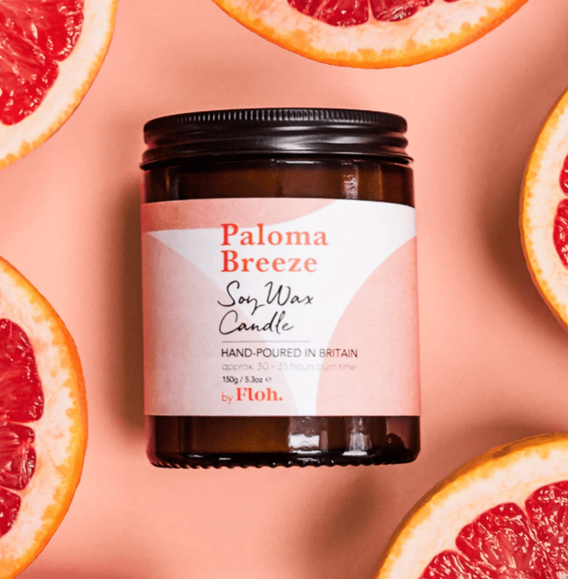 Paloma Breeze soy wax candle with grapefruit slices on a pink background