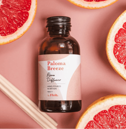 Paloma Breeze room diffuser bottle with grapefruit slices on a pink background