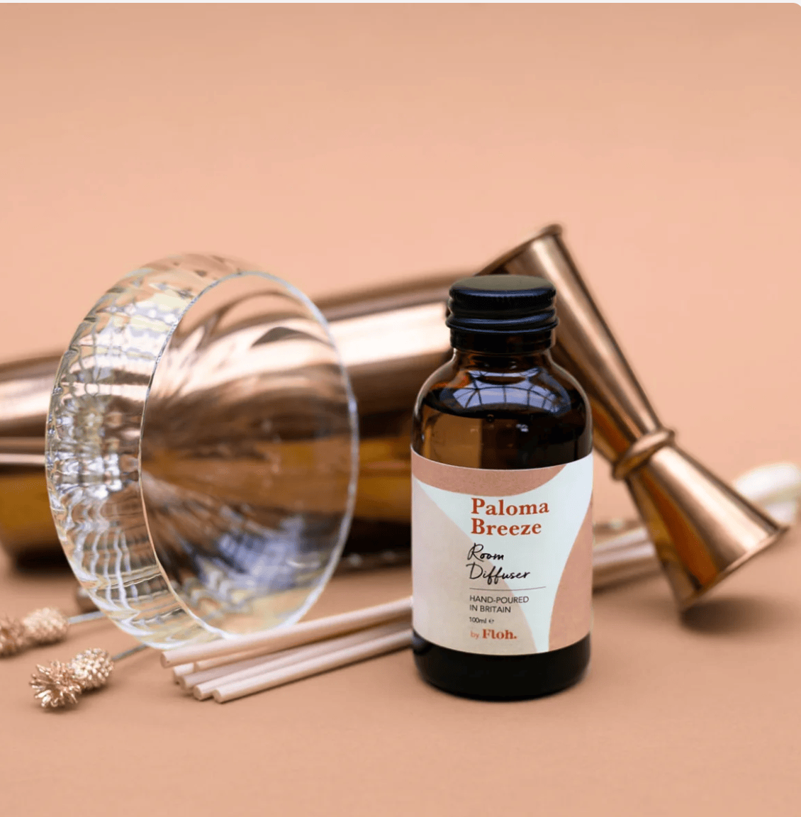 Paloma Breeze room diffuser bottle with sticks on a beige background