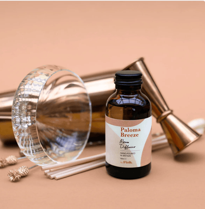 Paloma Breeze room diffuser bottle with sticks on a beige background