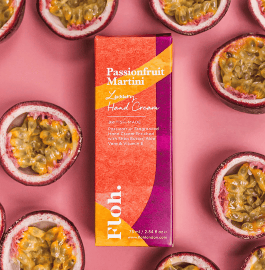 Passionfruit Martini hand cream box surrounded by passionfruit halves on a pink background