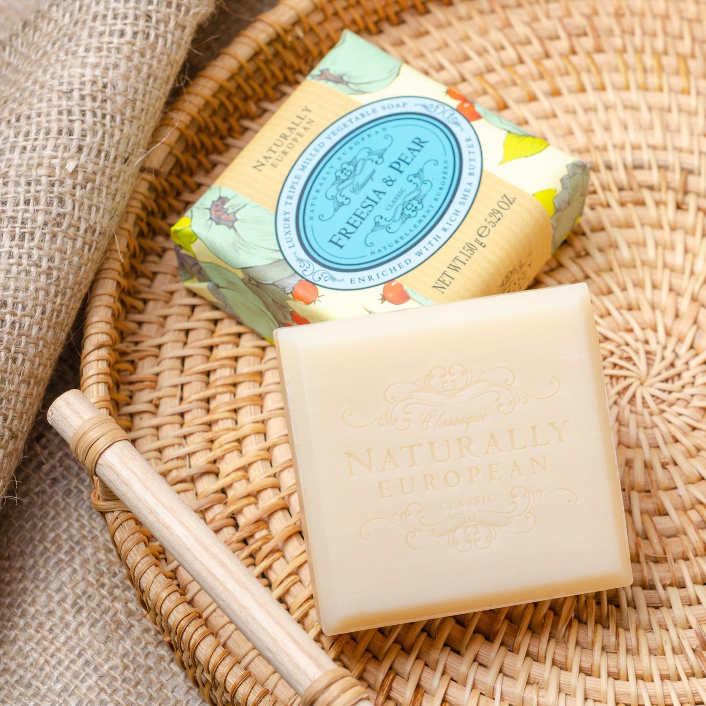 Bar of Somerset Toiletries Freesia & Pear soap with a decorative label on a woven basket