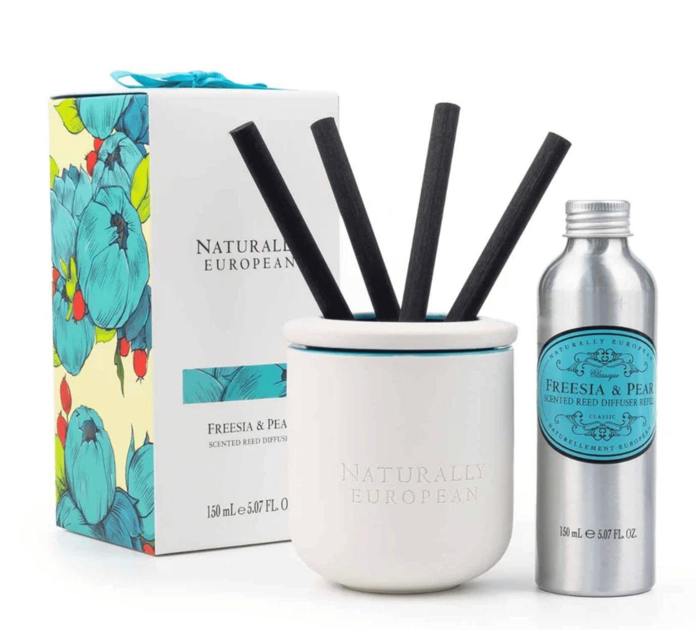 Naturally European Freesia & Peony scented reed diffuser set, featuring a white ceramic diffuser cup with four black reeds, a silver metal bottle of reed diffuser oil, and its floral-patterned retail box on a white background.