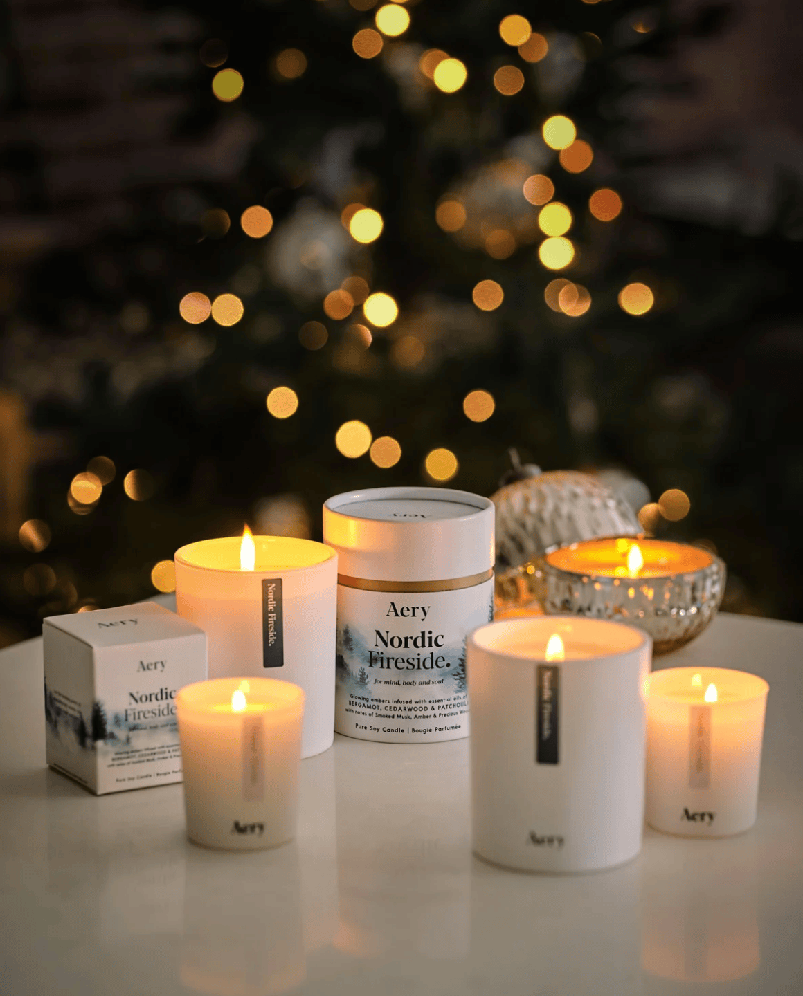 Aery candles and packaging on a table with a blurred Christmas tree in the background