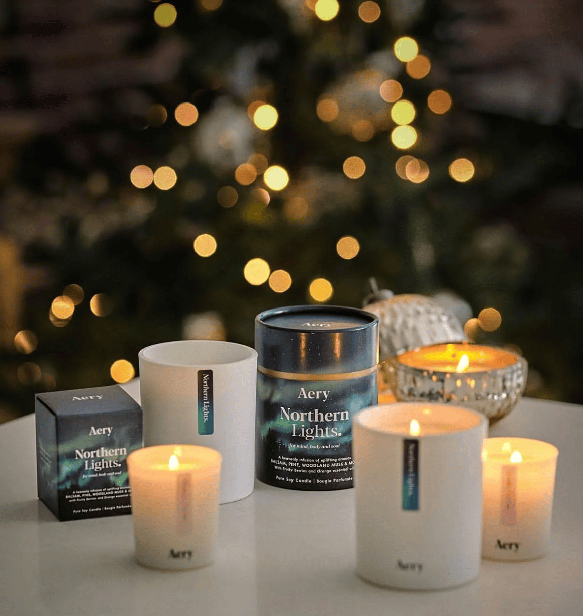 Aery candles and packaging with a blurred Christmas tree in the background