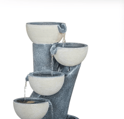 A four-tiered outdoor water fountain with textured, ribbed bowls in a light gray and white color scheme, set against a solid white background.