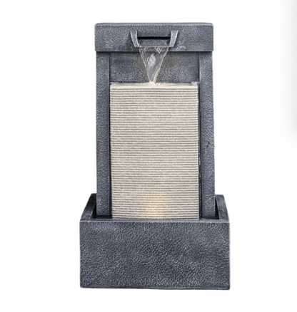 A modern geometric waterfall fountain with a textured dark gray stone-look base and frame, featuring a cascading water feature flowing into a ribbed central panel, shown against a plain white background.