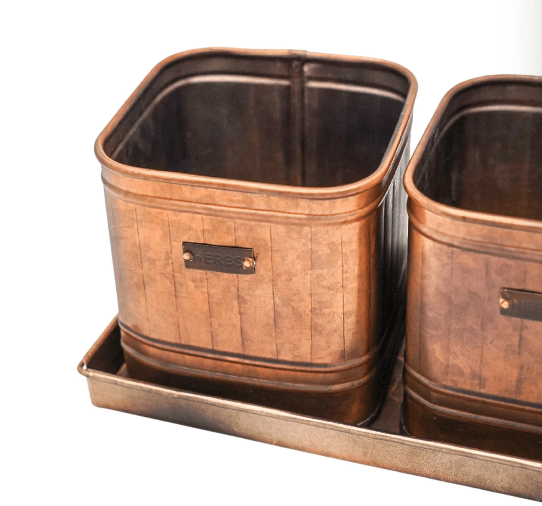 Two copper-colored metal planters on a matching tray with a white background