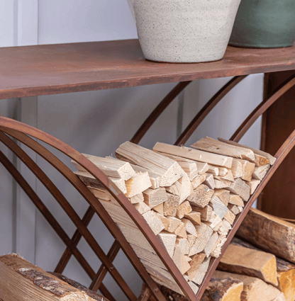 Wooden shelf with stacked firewood and decorative pots on a white wall background